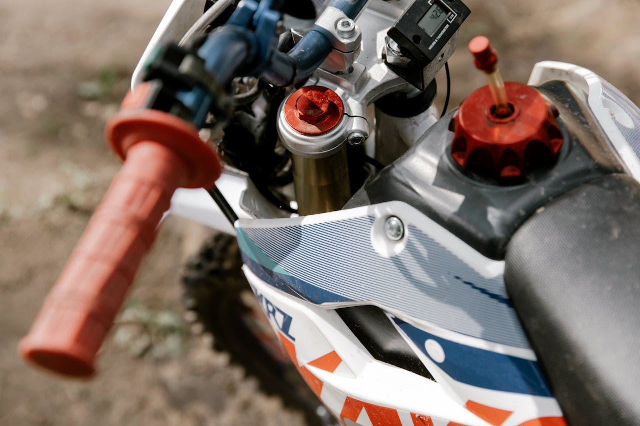 Detailed close-up of a dirt bike's handlebars showing grips and controls outdoors.
